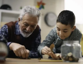 nieto y abuelo guardando en la hucha